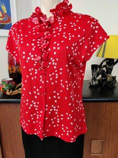 This is a red and white polyester blouse from Mardi Modes of New York in a medium to large size. The print is sweet white flying birds on a background of red and would be an easy care wash and wear. The blouse features a sunray ruffle neck ,red pearly buttons and dolman short sleeves. The condition is very good. Measurements are Bust 114cm Length 61cm Red Printed Short Sleeve Blouse, Red Collared Printed Blouse, Red Printed Collared Blouse, Polyester Blouse, Flying Birds, White Bird, Bird Print, Birds Flying, Large Bust