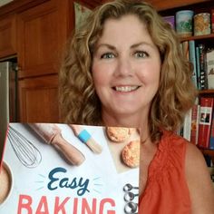 a woman holding up an easy baking book