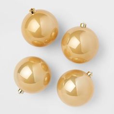 three shiny gold christmas balls on a white background with clippings to the side