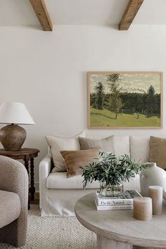 a living room filled with furniture and a painting on the wall above it's coffee table