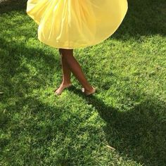 a woman in a yellow dress is standing on the grass