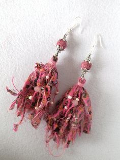 the earrings are made with pink yarn and beads