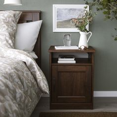 a bedroom with a bed, nightstand and plant on the side table in front of it