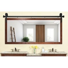 a bathroom with two sinks and a large mirror above the sink, along with a ladder leaning against the wall