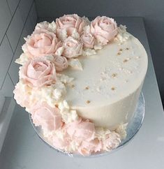 there is a white cake with pink flowers on the top and bottom layer, decorated with gold glitters