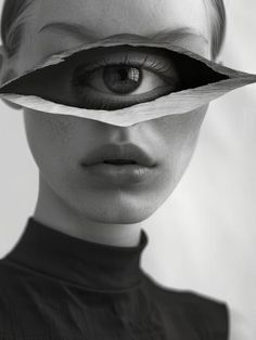 a black and white photo of a woman's face with paper covering her eyes