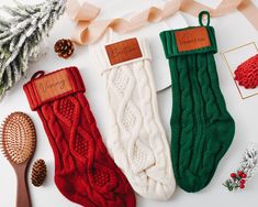 three christmas stockings and a brush on a white surface with ribbons, pine cones, and other holiday decorations