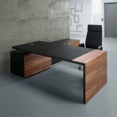 an office desk with a black chair in front of it and a concrete wall behind it