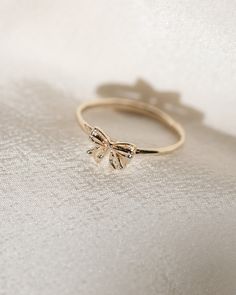 This perfectly petite coquette bow ring is inspired by the pendants worn by Marie Antoinette, adorned in ribbon and sealed with a bow. Bow measures approx. 7 x 7.5mm. Solid 14k yellow gold. Diamond Bow Ring, Coquette Rings, Ribbon Jewellery, Cute Jewelry Rings, Jewerly Ring, Ring Aesthetic, Rings For Couples, Dream Wishlist, Diamond Bows