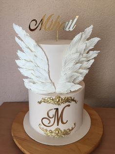 a cake decorated with white feathers and gold lettering