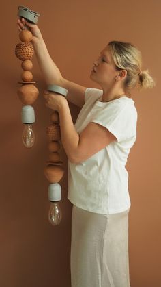 a woman is holding an object up to the wall