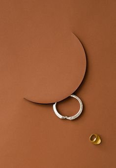 a pair of gold and silver rings sitting on top of a brown surface next to a circular object