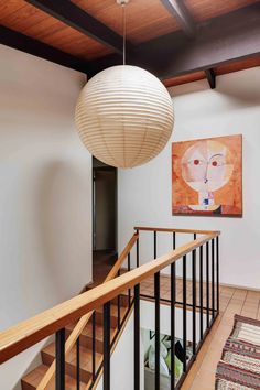 a large painting hangs on the wall next to a stair case with wooden handrails