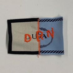 two pieces of fabric with the words duray on them and an orange stitch in the middle