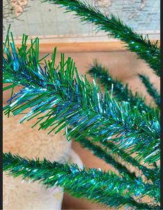 a close up of a green christmas tree with blue tinsel on it's branches