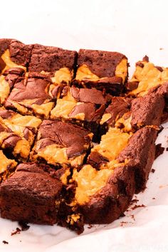 chocolate brownies with yellow frosting on top are sitting on parchment paper and have been cut into squares