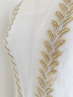 the back of a wedding dress with gold leaves on it