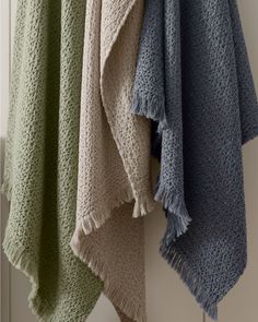 three towels hanging on a rack next to each other in different shades of green, beige and blue