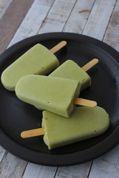 three popsicles sitting on top of a black plate