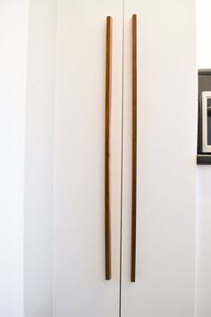 two wooden sticks sticking out of the side of a white wall next to a microwave