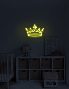 a neon yellow crown is on the wall above a crib in a dark room