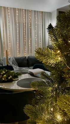 a living room with a christmas tree in the corner and lights on the wall behind it