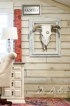 a living room with a chair and a wall hanging on it's side, next to a window