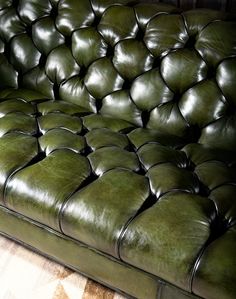 a green leather couch sitting on top of a rug