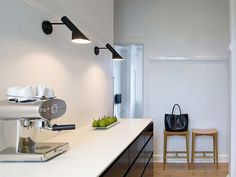 a kitchen with white counter tops and wooden chairs in front of the counter top, along with a black tote bag