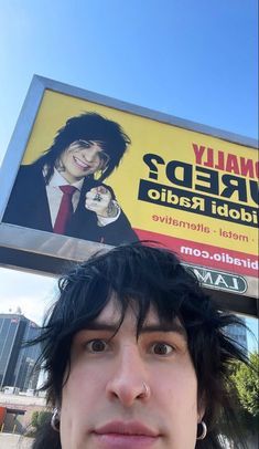 a man standing in front of a billboard with an ad on it's side