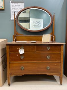 an old dresser with a mirror on top and some boxes in the corner next to it