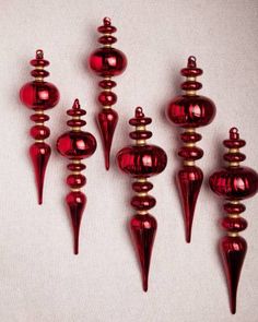 red glass ornaments are lined up against a white background