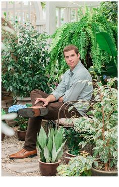 a man sitting on a bench surrounded by potted plants