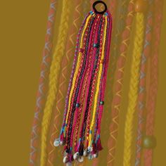 colorful beads hanging from a hook in front of a yellow and orange wall with rings