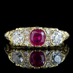 A gorgeous Victorian style carved half-hoop ring set with a bright natural pink ruby in the centre (approx. 0.65ct) flanked by sparkling old mine cut diamonds on either side (approx. 0.25ct each) and four smaller diamonds nestled in between. (approx. 0.60ct total).  Ruby is the birthstone of July. They've been a favourite of kings and emperors throughout history and are considered a stone of the heart. Its fiery pink/ red hue is symbolic of passion and said to bring good fortune in love and prov Antique Ruby Ring With Single Cut Diamonds, Heirloom Three Stone Ruby And Diamond Ring, Heirloom Three Stone Ruby Ring With Diamonds, Heirloom Three-stone Ruby And Diamond Ring, Heirloom Three-stone Ruby Ring With Diamonds, Heirloom Ruby Ring With Single Cut Diamonds, Antique Red Diamond Ring With Rose Cut Diamonds, Pink Ruby Ring With Single Cut Diamonds, Heirloom Ruby Ring With Three Stones