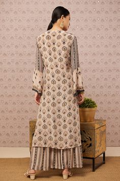 Beige angrakha kurta with all-over sarouk print, flared sleeves and sequin embroidery. Comes with palazzo.
Component: 2
Pattern: Print and Embroidery
Type Of Work: Sarouk Print and Sequin
Neckline: V neck
Sleeve Type: Flared Sleeves
Fabric: Crepe
Color: Beige
Other Details: 
Tie up on the side
Side slits
Closure: Hook front
Occasion: Sangeet - Aza Fashions Semi-stitched Block Print Long Sleeve Sets, Bohemian Kalamkari Print Straight Kurta Set, Bohemian Kalamkari Print Kurta Set, Bohemian Straight Kurta Sets For Transitional Season, Anarkali Kurta With Floral Print And Long Sleeves, Bohemian Straight Kurta Set With Dabka Detailing, Anarkali Style Long Sleeve Palazzo Set With Floral Print, Anarkali Palazzo Set With Floral Print And Long Sleeves, Bohemian Palazzo Set With Resham Embroidery And Long Sleeve