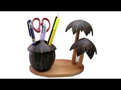 a wooden holder with two palm trees and pens