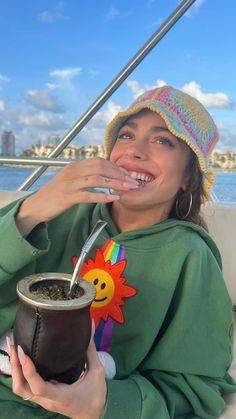 a woman sitting on top of a boat drinking out of a cup with a straw