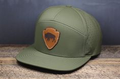 Richardson 169 7-Panel perforated cap in "Moss" color with stitched leather Bison Arrowhead leather patch Casual Leather Six-panel Snapback Hat, Leather Six-panel Snapback Hat For Outdoor, Leather Baseball Cap With Flat Bill For Outdoor, Leather Flat Bill Baseball Cap For Outdoor, Leather Snapback Hat For Outdoor Activities, Flat Bill Hats With Leather Sweatband For Outdoor, Outdoor Hats With Leather Sweatband And Flat Bill, 5-panel Leather Hat For Outdoor, 5-panel Leather Hats With Leather Patch