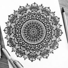 a black and white drawing of a flower with lots of details on the petals, surrounded by crayon pencils