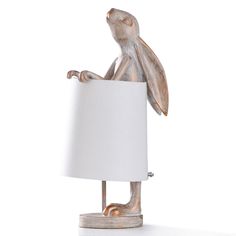 a white lamp with a wooden rabbit holding a paper shade on it's side