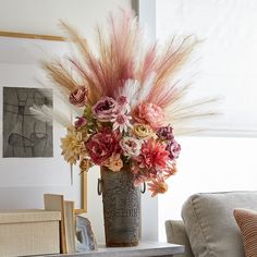 a vase filled with lots of flowers on top of a table next to a couch