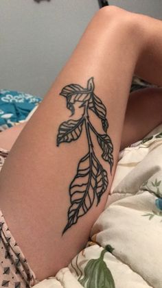 a woman's leg with a tattoo on it that has leaves growing out of it