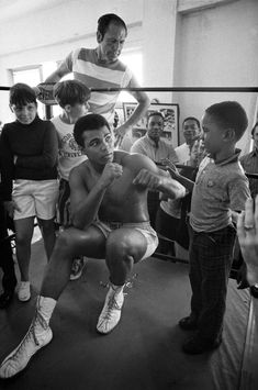 a group of people standing around each other in front of a man with no shirt on