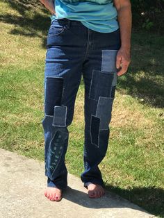 a woman in blue shirt standing on sidewalk next to grass and trees with her hands in her pockets