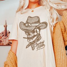 *Ask About Bulk Discounts* Cowboy Killer Shirt, Western Graphic Tee, Western Halloween Shirt, Rodeo Shirt, Cowgirl Shirt, Retro Cowboy Shirt, Retro Western Shirt .: 100% Airlume combed and ringspun cotton (fiber content may vary for different colors) .: Light fabric (4.2 oz/yd² (142 g/m .: Retail fit .: Tear away label .: Runs true to size Shipping & Processing:  Please allow 1-7 business days for processing. It may be processed sooner, and you will be updated as soon as it ships. Shipping can t Rodeo Short Sleeve Shirt, Pre-shrunk, Cotton Skull Print Shirt For Fall, Fall Cotton Shirt With Skull Print, Fall Skull Print Cotton Shirt, White Graphic Print Shirt For Rodeo, Casual Crew Neck Shirt For Rodeo, Pre-shrunk Tops For Rodeo In Fall, Crew Neck Graphic Tee For Rodeo, Graphic Tee Crew Neck Shirt For Rodeo