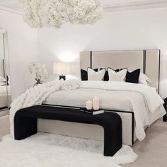 a white bedroom with black and white decor on the bed, chandelier and mirror