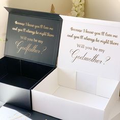 two white boxes with gold foil lettering on the inside and one black box with gold foil lettering on the outside