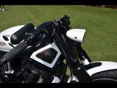 a white and black motorcycle parked on top of a lush green field