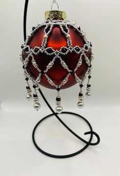 a red ornament with silver beads and a black cord